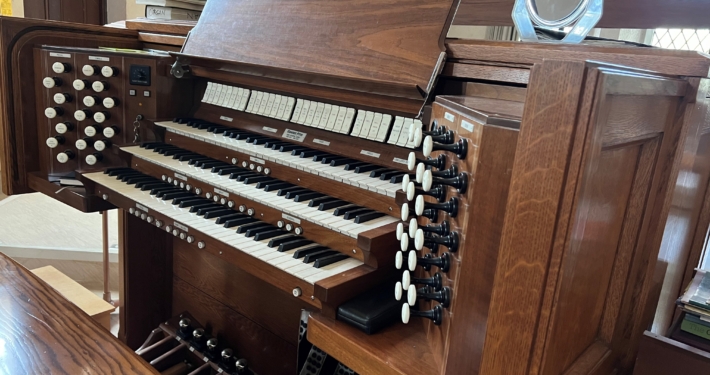 Church pipe organ console with three keyboards, pedals, and stops.