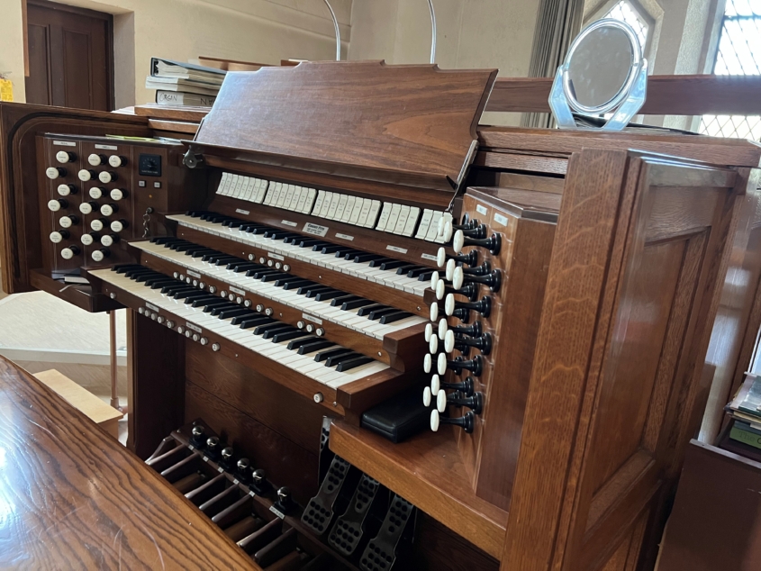 Church pipe organ console with three keyboards, pedals, and stops.
